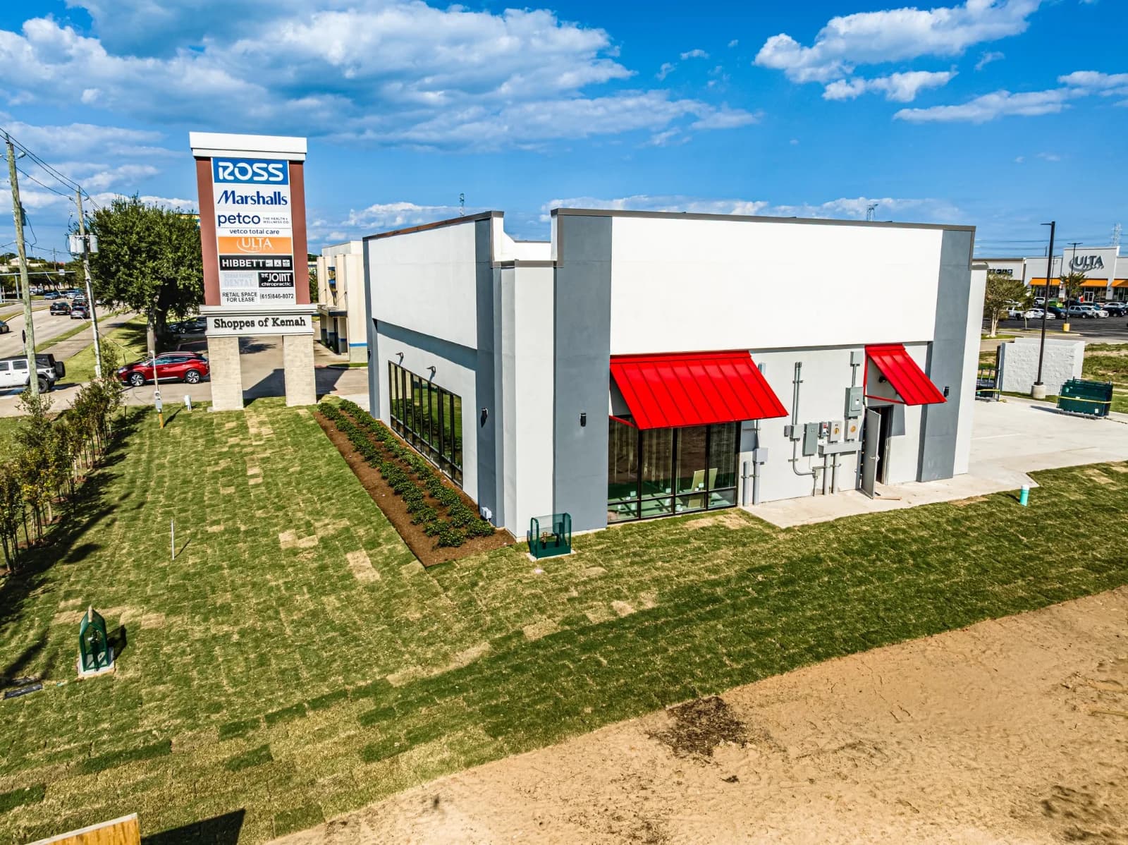 Side elevation of the finished Verizon Bryan store with landscaping and parking