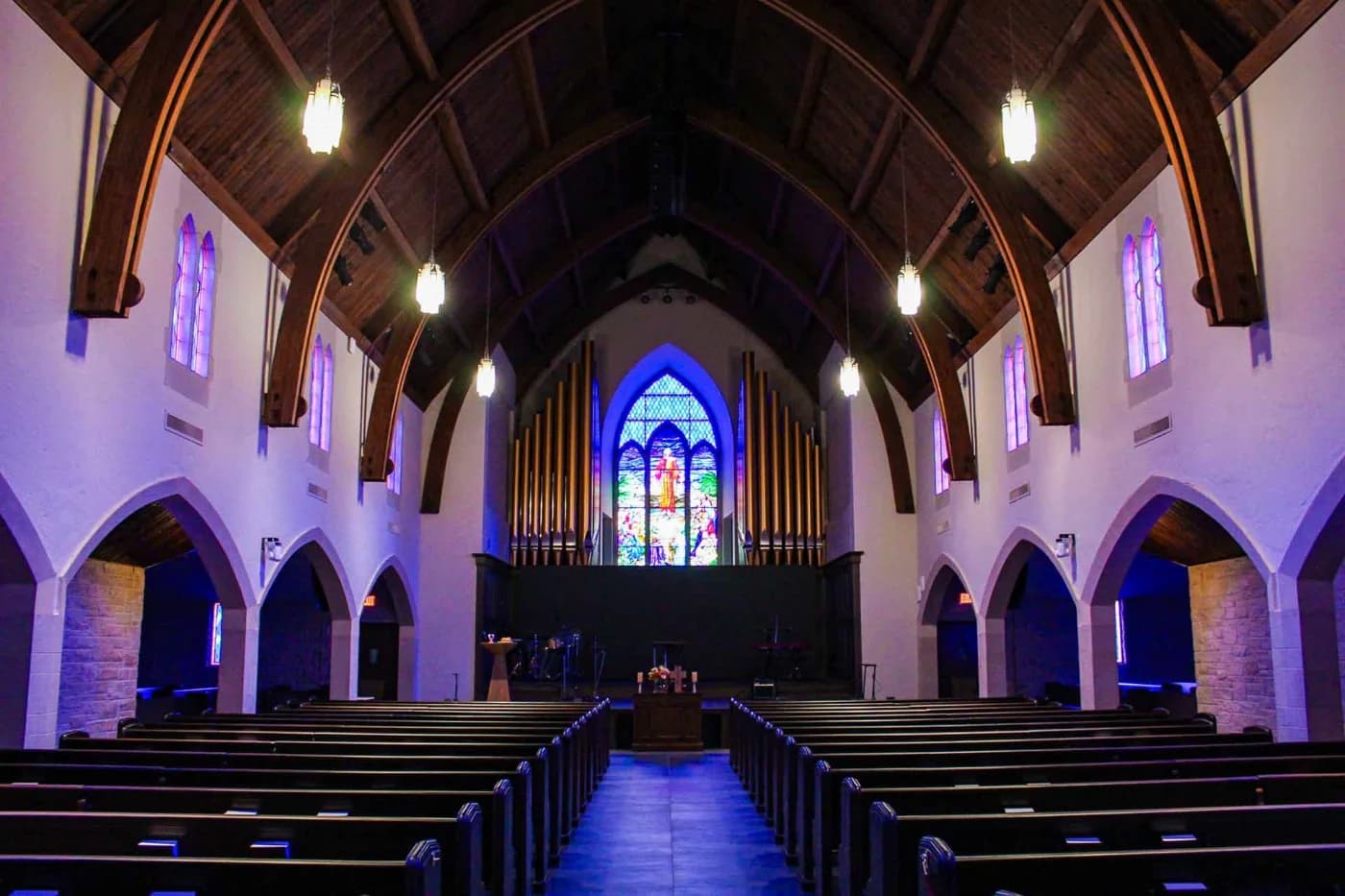 Church nave with vaulted stone arches, a timber ceiling and stained glass windows